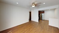 This single-floor unit offers a clean, functional layout with consistent wood-style flooring running throughout all rooms, creating a cohesive and warm aesthetic. The kitchen is a standout feature, outfitted with rich espresso-toned cabinetry, granite-style countertops, and a mosaic tile backsplash in neutral earth tones. Stainless steel appliances — including a refrigerator, electric range, and microwave — complete the space, which also benefits from recessed lighting overhead. An adjacent dining or flex area provides additional room for entertaining or everyday use. The living area is open and airy, with crisp white walls, recessed lighting, a ceiling fan, and a large window fitted with vertical blinds that allow for natural light. The bedrooms continue the same flooring and feature ceiling fans, recessed lighting, and windows with vertical blinds, offering a bright and comfortable retreat. The bathroom is finished in clean white tiling with a full soaking tub and shower combination, wood-style flooring, and a vanity with granite-style countertops. Throughout the unit, the design emphasizes simplicity and functionality, with neutral tones and modern finishes that create a move-in-ready environment.