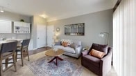 Located at Chelsea Place in Toledo, Ohio, this one-bedroom, one-bathroom residence offers a thoughtfully designed single-floor layout that maximizes every square foot. The open-concept living and kitchen area serves as the heart of the home, where rich hardwood-style flooring flows through the kitchen and transitions into plush carpet in the living space. The kitchen is outfitted with white cabinetry, glass-front upper cabinets, light stone countertops, track lighting, and a peninsula breakfast bar with seating — ideal for casual dining. The living room is bright and welcoming, featuring crown molding, neutral gray walls, and a large sliding glass door that fills the space with natural light and opens to an outdoor view. The bedroom is a comfortable retreat, carpeted and well-lit by a broad window, with ample room for a full bedroom suite. The bathroom includes a tub-shower combination with tile surround, a white vanity with stone countertop, and tile flooring. Throughout the residence, six-panel white doors and a consistent neutral color palette create a clean, cohesive aesthetic. This residence combines practical functionality with refined finishes in a convenient Toledo location.