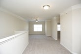 This single-floor residence presents a cohesive, neutral-toned interior highlighted by crown molding and ceiling fans throughout. The expansive living area features plush wall-to-wall carpeting and flows into a long hallway corridor with natural light filtering through a window at the far end. A half-wall partition subtly divides the living space from the kitchen area.

The kitchen is outfitted with warm honey-toned cabinetry, dark laminate countertops, and a full suite of black appliances, including an electric range, dishwasher, and over-the-range microwave. Crown molding carries through into the kitchen, maintaining design consistency across the space.

The bedrooms are generously sized, each featuring soft carpeting, ceiling fans, crown molding, and large windows that bring in natural light. One bedroom includes a walk-in closet with wire shelving and an additional standard closet, providing ample storage.

The bathroom is cleanly appointed with tile flooring, a tub-shower combination featuring a black and white tile accent border, a dark countertop vanity, and warm wood cabinetry. A dedicated laundry nook accommodates a full-sized washer and dryer with an overhead wire storage shelf, adding practical functionality to the unit.