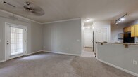 This single-story residence in Columbus, Georgia offers a well-organized layout designed for comfortable everyday living. The open living and dining area is finished with neutral gray walls, crisp crown molding, and plush wall-to-wall carpeting, creating a cohesive and inviting atmosphere. A ceiling fan overhead and track lighting add functional illumination throughout. The space connects seamlessly to a kitchen equipped with warm honey-toned cabinetry, black appliances, and a convenient breakfast bar that serves as a natural dividing point between the cooking and living areas.

Multiple carpeted bedrooms provide comfortable retreats, each featuring neutral walls and adequate natural light from windows with blinds. One bedroom benefits from a ceiling fan, while another includes a private door leading to an adjacent space, offering added flexibility. An exterior door in one room provides direct outdoor access.

The bathrooms are finished with warm wood vanities, white countertops, tile flooring, and tub-shower combinations enclosed by decorative curtains. A utility area with a built-in shelf and electrical panel access adds practical functionality. Throughout the home, consistent neutral tones, white six-panel doors, and clean baseboards contribute to a tidy, move-in ready presentation.