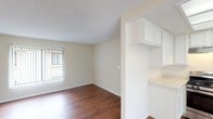 This single-floor unit offers a practical and well-organized layout designed for comfortable everyday living. The open-concept living and dining area is a standout feature, showcasing warm hardwood-style flooring that runs throughout the main living spaces. Large windows fitted with vertical blinds allow natural light to fill the room, creating a bright and airy atmosphere. A ceiling fan adds both function and a finishing touch to the space.

The kitchen is thoughtfully designed with white cabinetry, light countertops, and stainless steel appliances, including a gas range and dishwasher. A built-in skylight panel above the kitchen provides additional illumination, while a window over the sink brings in natural light. A pass-through opening connects the kitchen to the dining area, enhancing the open feel of the layout.

The bedrooms are finished with plush carpeting and neutral walls, offering a comfortable and quiet retreat. Each room benefits from natural light through windows with vertical blinds. The bathroom features a white vanity with an integrated sink, a large mirror with overhead lighting, and clean, understated finishes throughout.

Overall, the unit presents a cohesive, neutral aesthetic with durable finishes, making it a functional and inviting space ready for personal touches.