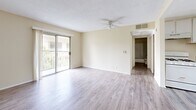 Located at 843 Irolo St in the Koreatown neighborhood of Los Angeles, this one-bedroom, one-bathroom unit offers a well-organized single-floor layout comprising a living room, bedroom, kitchen, and hallway. Throughout the space, light-toned wood-style flooring provides a clean, cohesive look that complements the warm beige walls and textured ceilings found in each room.

The living room is a bright, open area featuring a ceiling fan and a sliding glass door that opens to a private balcony, filling the room with natural light and views of surrounding greenery. An adjacent bathroom is conveniently accessible from this main living area.

The bedroom is a comfortable, well-proportioned space also equipped with a sliding glass balcony door, allowing for additional natural light and outdoor access. A set of double sliding-door closets provides ample built-in storage, making the room both functional and practical.

The kitchen offers generous counter space with dark laminate countertops, a double-basin sink, and an abundance of white cabinetry — both upper and lower — delivering substantial storage. A window above the sink allows natural light to brighten the workspace. The hallway connects the main rooms efficiently, contributing to a logical and easy-to-navigate floor plan. Overall, the unit presents a clean, neutral palette well-suited for comfortable urban living.