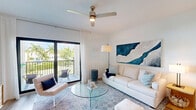 Located at Waterfront Crossing in Greenacres, FL, this two-story residence offers 2 bedrooms and 3 bathrooms across a thoughtfully designed floor plan. The main living level hosts an open-concept kitchen, dining, and living area finished with warm hardwood-style flooring throughout. The kitchen is equipped with stainless steel appliances, light wood cabinetry extending to the ceiling, a quartz-topped island with bar seating, and pendant lighting — combining style with functionality. The living area features soaring ceilings, a ceiling fan, and flows seamlessly into the dining space, creating an airy, inviting atmosphere. Both bedrooms are well-appointed with hardwood-style floors, ceiling fans, and ample natural light from large windows with outdoor views of the surrounding greenery. The primary bedroom includes a spacious walk-in closet with built-in shelving. Three clean, modern bathrooms feature light wood vanities, tile surround tub-shower combinations, and bright, neutral finishes. A private garage on the ground level provides secure parking and additional storage space. The home's consistent white walls, natural light, and cohesive design elements create a bright, contemporary ambiance throughout.