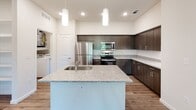 Located on Edgeworth Bend in Austin, TX 78754, this single-story home offers a thoughtfully designed open layout that connects the kitchen and living areas seamlessly. The kitchen serves as the centerpiece of the space, featuring a large island with a granite countertop and undermount sink, dark espresso-toned cabinetry, subway tile backsplash, and a full suite of stainless steel appliances including a refrigerator, electric range, and microwave. Pendant lighting above the island adds a modern touch, while wood-look flooring grounds the space with warmth and durability.

The living area extends from the kitchen through an arched entryway, finished with plush carpet and a ceiling fan. Bedrooms are carpeted and well-proportioned, each offering natural light through slatted-blind windows and generous closet space with built-in wire shelving. The bathrooms mirror the kitchen's aesthetic, presenting granite-topped dark vanities, wood-look flooring, and full tub-shower combinations. A dedicated laundry area houses a full-sized Whirlpool washer and dryer alongside additional shelving. Clean white walls and recessed lighting throughout contribute to a bright, contemporary ambiance well-suited to everyday living.