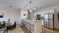 Located at 3044 Hidden Forest Ct in Marietta, GA, this multi-floor residence offers four bedrooms, five bathrooms, and a well-organized layout across three floors of comparable size. The ground floor features an open-concept kitchen and living room with light wood-style flooring throughout. The kitchen is outfitted with white cabinetry, a mosaic tile backsplash, stainless steel appliances including a refrigerator, electric range, and built-in microwave, and a breakfast bar with pendant lighting — ideal for both cooking and casual dining. The adjoining living room is bright and inviting, with large windows dressed in sheer curtains that allow natural light to fill the space. The bedrooms are comfortably sized, each with windows offering views of the surrounding greenery, ceiling fans, and dedicated closets. The primary bedroom provides a functional and cozy retreat. Five bathrooms serve the home, each featuring a single-sink vanity, toilet, and shower-tub combination with clean, neutral finishes and wood-style flooring. A dedicated laundry room houses a full-size washer and dryer with wire shelving above. Staircases connect all three levels, and a hallway ties the layout together efficiently. The overall aesthetic is clean, modern, and practical throughout.