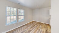 Located at Weatherstone Park in New Bern, North Carolina, this single-story one-bedroom, one-bathroom unit offers a well-organized and functional layout. Wood-look plank flooring runs consistently throughout, creating a clean, cohesive aesthetic across every room.

The combined living and dining area is bright and open, featuring multiple windows that invite natural light and provide views of the surrounding wooded landscape. A ceiling fan overhead adds practical comfort to the space.

The galley-style kitchen is efficiently designed with ample white cabinetry lining both sides, light countertops, a double-basin sink, and white appliances including a range, refrigerator, and dishwasher. A window at the end of the kitchen allows additional natural light to filter in.

The bedroom is a generously proportioned room with two closets, a ceiling fan, and windows on multiple walls that bring in plenty of daylight and wooded outdoor views. Three total closets throughout the unit provide notable storage capacity for a residence of this size.

The bathroom is clean and straightforward, featuring a tub/shower combination, a toilet, and a vanity with white cabinetry and a countertop-mounted sink. The wood-look flooring continues here as well, maintaining consistency with the rest of the home. Neutral wall tones throughout lend a calm, move-in-ready ambiance.