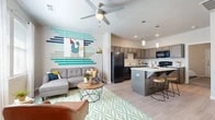 This thoughtfully designed single-floor unit offers a seamless open-concept layout connecting the living area and kitchen. The living room features light wood-style flooring, a ceiling fan, large windows that invite natural light, and a vibrant accent wall adorned with colorful horizontal wall art that adds a contemporary, artistic touch to the space.

The kitchen is a functional centerpiece, equipped with rich gray-toned cabinetry, light countertops, and black appliances including a refrigerator, stove, microwave, and dishwasher. A peninsula island with bar seating and stylish pendant lighting above serves as both a prep area and casual dining space, creating a natural transition between the kitchen and living areas.

The bedroom is a comfortable retreat featuring a ceiling fan, windows with natural light, and warm, neutral tones that contribute to a relaxed ambiance. The full bathroom is well-appointed with dark wood cabinetry, a large vanity mirror, and light flooring that complements the overall aesthetic of the unit.

A dedicated in-unit laundry room provides added convenience, complete with a full-size washer and dryer, built-in shelving, and additional storage space. Light wood-style flooring flows consistently throughout the unit, unifying the space with a clean, modern feel.