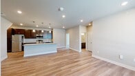 This well-appointed single-floor residence offers a thoughtfully designed open-concept layout, seamlessly connecting the living area and kitchen into one expansive, light-filled space. Light wood-tone flooring flows consistently throughout, lending a clean, cohesive aesthetic to every room.

The kitchen serves as a focal point, featuring rich dark-wood cabinetry, granite countertops, stainless steel appliances including a range, microwave, and refrigerator, and a generous island with pendant lighting overhead and a built-in sink — ideal for both meal preparation and casual dining.

The primary bathroom is well-equipped with a double-sink vanity topped with granite, dark cabinetry with brushed nickel hardware, and wood-look flooring. A secondary full bathroom offers a single-sink granite vanity, a soaking tub, and matching finishes. Both bathrooms maintain a consistent, refined design language.

The bedroom includes a ceiling fan, a wide window allowing natural light and outdoor views, and access to a spacious walk-in closet outfitted with wire shelving and hanging rods for ample storage.

A dedicated laundry room houses a full-size front-loading washer and dryer alongside additional wire shelving. Throughout the residence, neutral wall tones, recessed lighting, and clean architectural lines create a modern, functional, and inviting living environment.