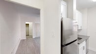 Located on Wilshire Boulevard in the heart of Los Angeles, this single-floor unit has been thoughtfully updated with contemporary finishes throughout. Light wood-tone flooring runs consistently across the living spaces, creating a cohesive and airy feel. The living area is well-proportioned and bright, featuring a ceiling fan with integrated lighting and a spacious closet with panel-style doors, offering ample storage. An adjacent room provides flexible use as a bedroom or office, highlighted by a double-pane window that invites natural light and features its own ceiling fan. The kitchen is efficiently designed with crisp white shaker-style cabinetry, a subway tile backsplash, dark quartz countertops, a stainless steel sink, and stainless steel appliances including a dishwasher and refrigerator, with a window allowing natural light to brighten the workspace. The bathroom is cleanly appointed with marble-look tile flooring, a soaking tub with a tiled surround, a compact grey vanity with a mirror, and a window for ventilation. Clean white walls and brushed nickel hardware accents tie the design together throughout, creating a polished and move-in-ready space.
