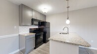 Located at 11270 Fourth St N in Saint Petersburg, Florida, this single-floor residence offers a thoughtfully designed layout with modern finishes throughout. The open-concept living and dining area features a combination of durable wood-look flooring and plush carpeting, creating a warm and functional environment. Natural light flows in through large windows, with views of the surrounding exterior.

The kitchen is a standout feature, showcasing granite countertops, a peninsula with an undermount sink and pendant lighting overhead, and grey shaker-style cabinetry. A classic white subway tile backsplash complements the black appliances, which include a refrigerator, electric range, and built-in microwave. The space is further enhanced by a textured ceiling throughout.

The bedroom is generously sized with soft carpeting underfoot, a large window that invites natural light, and direct access to a walk-in closet. The bathroom is clean and functional, featuring a tiled tub/shower combo, wood-look flooring, grey vanity cabinetry, and granite countertops that mirror the kitchen's aesthetic. A hallway connects the main living areas to the private spaces, providing a well-organized and efficient floor plan suited for comfortable everyday living.