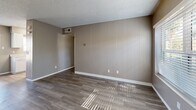 Located at 1345 S Kolb Rd in Tucson, Arizona, this single-story, one-bedroom unit offers a practical and efficient layout across a compact footprint. The combined kitchen and living area forms the heart of the space, featuring durable hardwood-style flooring, neutral taupe walls, and a textured popcorn ceiling. Large windows allow natural light to fill the living room, creating a bright and welcoming atmosphere. A distinctive vertical-paneled accent wall adds a subtle design element to the living area.

The galley-style kitchen is well-appointed with white cabinetry, light quartz-style countertops, a stainless steel double-basin sink, a gas range, and a stainless steel refrigerator. Light wood-tone flooring and a window above the sink keep the kitchen feeling airy and functional.

The bedroom is a comfortable, carpeted retreat featuring a window with outdoor views of surrounding greenery, a textured ceiling, and neutral wall tones that carry throughout the unit. A dedicated closet provides convenient storage directly off the bedroom.

Overall, the unit presents a clean, move-in-ready aesthetic with consistent neutral tones, white trim, and practical finishes throughout, making it a straightforward and functional living space in Tucson's east side.