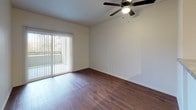 This single-floor unit offers a thoughtfully designed layout with a cohesive blend of functional finishes throughout. The living area is bright and open, featuring warm wood-style flooring, a ceiling fan with light fixture, and a sliding glass door with vertical blinds that opens to a private balcony with outdoor views of surrounding greenery. The kitchen is efficiently arranged with light wood cabinetry, granite-style countertops, and stainless steel appliances including an electric range and over-the-range microwave, providing ample workspace for everyday use. A pantry or closet door is conveniently located just off the kitchen for additional storage. The bedroom is carpeted for comfort and includes a ceiling fan, a window that allows natural light and views of the tree line, and a baseboard heating unit. The bathroom is cleanly finished with wood-style flooring, a single-sink vanity topped with a granite-style counter and light wood cabinetry, a wall-mounted mirror, and a full bathtub and shower combo enclosure. Overall, the unit presents a clean, neutral palette with practical finishes designed for comfortable everyday living.