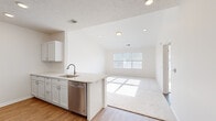 This well-designed single-floor residence offers a thoughtful layout across one bedroom, two bathrooms, a living room, kitchen, and a closet. The open-concept kitchen and living area form the heart of the home, where wood-look flooring transitions seamlessly between the two spaces. The kitchen is equipped with white shaker-style cabinetry, light countertops, a stainless steel refrigerator, range, microwave, dishwasher, and a sink set into a peninsula that connects the kitchen to the living area. Recessed lighting and a vaulted ceiling add a sense of openness to this shared space. The living room features plush carpeting and a large window that fills the room with natural light. The bedroom is a well-proportioned retreat finished with soft carpet and a wide window offering pleasant outdoor views. A dedicated closet provides practical storage. Both bathrooms are clean and functional, with one featuring a full tub-and-shower combination, a white vanity with storage, and wood-look flooring. Throughout the residence, bright white walls, consistent finishes, and an abundance of natural light create a clean, airy, and inviting atmosphere.