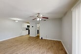 Located on Jefferson Highway in Baton Rouge, Louisiana, this single-floor, one-bedroom, one-bathroom unit offers a clean, functional layout with consistent design choices throughout. Light-toned wood-look flooring runs seamlessly across every room, complementing the soft gray walls and bright white trim for a cohesive, modern aesthetic.

The open living area is spacious and bright, anchored by a ceiling fan with a light fixture and a large sliding glass door fitted with vertical blinds that allows natural light to fill the room. The kitchen flows directly from the living space and is well-equipped with crisp white shaker-style cabinetry, granite-look countertops, and black appliances including a range, over-the-range microwave, and refrigerator.

The generously sized primary bedroom features its own ceiling fan, a natural-light window with blinds, and a sizable closet accessible via bifold doors. The bathroom is clean and efficient, outfitted with a white vanity featuring granite-look countertops, a tub-shower combination, and matching wood-look flooring. A hallway connects the bedroom and bathroom, adding a sense of privacy to the sleeping quarters. The unit presents a practical, move-in-ready living environment throughout.