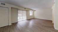 Located at 7 Colony Blvd in Wilmington, Delaware, this single-floor residence offers a practical and comfortable layout designed for everyday living. The living area is a standout feature, characterized by durable hardwood-style flooring that extends throughout the space, a textured ceiling, and a large sliding glass door fitted with vertical blinds that floods the room with natural light and provides views of the surrounding outdoor greenery. An additional window further enhances the brightness and openness of this main living space. The layout flows naturally from the entryway, which includes a closet for storage, into the open living and dining area. A pendant light fixture marks the dining area, and multiple closets along the hallway offer generous storage solutions. The galley-style kitchen is efficiently arranged with warm wood-toned cabinetry, light countertops, a stainless steel sink, and white appliances including a refrigerator, stove, and dishwasher. The bathroom features a full-size soaking tub and shower combination with clean white tile surround and chrome fixtures, maintaining a crisp and functional aesthetic. Throughout the residence, neutral wall tones and consistent flooring create a cohesive and move-in ready environment.
