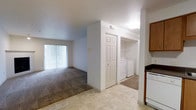 This single-floor, 2-bedroom, 1-bathroom residence is designed for comfortable, everyday living with a functional and well-organized layout. The open living area features wall-to-wall carpeting and is filled with natural light streaming through large vertical-blind-covered sliding glass doors, which lead to an outdoor space and lend the room an airy, welcoming feel. The transition from the living area to the kitchen is defined by a change to tile flooring, creating a clear and practical delineation between spaces. The kitchen is equipped with warm wood-toned cabinetry and includes a dishwasher, offering convenient amenities for daily use. A standout feature of this residence is the dedicated in-unit laundry area, which houses a full-size washer and dryer behind a set of classic six-panel closet doors — a rare and practical convenience. Adjacent to the laundry area is an open storage closet with built-in shelving, providing ample organizational space. The textured ceilings throughout add a subtle architectural detail, while the neutral color palette across all areas creates a clean, move-in-ready environment. Overall, the space balances practicality with comfort, making it a well-appointed home for everyday living.