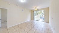 Located at 750 NW 8th St in Florida City, Florida, this single-floor unit offers a practical and comfortable layout across a compact yet efficiently organized footprint. Light-toned ceramic tile flooring runs consistently throughout every room, creating a cohesive and easy-to-maintain interior.

The kitchen is thoughtfully designed with dark espresso cabinetry, tile backsplash, light countertops, and a full suite of white appliances including a refrigerator, electric range, built-in microwave, and dishwasher. A peninsula counter provides a natural divider between the kitchen and the living area, adding casual seating or prep space.

The open living area is bright and airy, featuring a ceiling fan and a sliding glass door that leads to a private balcony with views of the surrounding greenery. Natural light fills the space, enhancing its open feel.

The spacious primary bedroom includes a ceiling fan, a window with outdoor views, and ample room for furnishings. The full bathroom is clean and well-appointed, featuring beige tile surround on the tub/shower combo with chrome grab bars, a built-in niche, a dark wood vanity with light countertop, and tile flooring. A washer and dryer are also included within the unit, adding everyday convenience to this functional Florida City home.