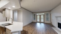 Located at 1200 S Dairy Ashford Rd in Houston, TX, this single-story 2-bedroom, 2-bathroom residence offers a thoughtfully designed open-concept layout. The spacious living room features rich hardwood-style flooring, crown molding, a cozy fireplace, and a set of French doors flanked by large windows that bathe the space in natural light and offer pleasant outdoor views. The adjacent kitchen is well-equipped with stainless steel appliances, a gas range, a subway tile backsplash, shaker-style cabinetry, and a generous white quartz peninsula with an undermount sink — ideal for both cooking and casual dining. Both bedrooms are carpeted for comfort and receive natural light through large windows with blinds. Each bedroom is served by its own closet with wire shelving systems providing organized storage. The bathrooms are finished with wood-look flooring, clean white vanities, and tiled tub-shower combinations. A dedicated laundry room houses a full-sized washer and dryer. The overall aesthetic is clean and modern, with a neutral palette throughout that creates a bright, inviting atmosphere well-suited for comfortable everyday living.
