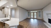 Located at 1200 S Dairy Ashford Rd in Houston, TX, this single-story 2-bedroom, 2-bathroom residence offers a thoughtfully designed open-concept layout. The spacious living room features rich hardwood-style flooring, crown molding, a cozy fireplace, and a set of French doors flanked by large windows that bathe the space in natural light and offer pleasant outdoor views. The adjacent kitchen is well-equipped with stainless steel appliances, a gas range, a subway tile backsplash, shaker-style cabinetry, and a generous white quartz peninsula with an undermount sink — ideal for both cooking and casual dining. Both bedrooms are carpeted for comfort and receive natural light through large windows with blinds. Each bedroom is served by its own closet with wire shelving systems providing organized storage. The bathrooms are finished with wood-look flooring, clean white vanities, and tiled tub-shower combinations. A dedicated laundry room houses a full-sized washer and dryer. The overall aesthetic is clean and modern, with a neutral palette throughout that creates a bright, inviting atmosphere well-suited for comfortable everyday living.