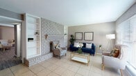 This single-story 1-bedroom, 1-bathroom residence offers a thoughtfully designed layout that maximizes comfort and functionality. The living room serves as the heart of the home, anchored by a striking floor-to-ceiling painted brick fireplace flanked by built-in shelving, creating a warm and inviting focal point. Large windows allow abundant natural light to fill the space, which features neutral-toned walls and light tile flooring throughout the main living areas. The entry area flows seamlessly into the living room, reinforcing the open, airy feel of the space.

The galley-style kitchen is efficiently arranged with white cabinetry, laminate countertops, a double-basin sink, and black appliances including a refrigerator and range. Tile flooring continues into this space, making it easy to maintain.

The bedroom is a peaceful retreat, finished with wood-look laminate flooring, vaulted ceilings, a ceiling fan with light fixture, and a generous window that brings in soft natural light. The full bathroom is clean and functional, featuring a wide white vanity with ample cabinet storage, tile flooring, and a tub-shower combination with tile surround.

Overall, the space presents a cohesive neutral palette with modern touches, offering a comfortable and practical living environment.