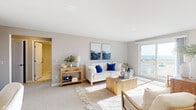 Located at 151 Ocean Rd in Narragansett, Rhode Island, this single-floor coastal retreat offers a thoughtfully designed layout with a relaxed, beach-inspired aesthetic throughout. The spacious living room serves as the heart of the space, featuring soft neutral carpeting, large sliding glass doors, and direct access to a private balcony with sweeping ocean views. Natural light pours in generously, creating a warm and airy ambiance that complements the coastal décor. A separate dining area features hardwood-style flooring and a wide window that invites additional natural light, making it an ideal spot for casual meals. The kitchen is efficiently designed with white shaker-style cabinetry, light countertops, hardwood-style flooring, and stainless steel appliances including a dishwasher, range, and refrigerator. The bedroom is comfortably proportioned with plush carpeting, a bright window, and generous closet space. The bathroom is finished with crisp white subway tile in a glass-enclosed walk-in shower, white tile flooring, and a clean vanity — offering a polished, modern feel. Throughout the space, a cohesive palette of warm neutrals and coastal blues creates a serene atmosphere ideally suited to the Narragansett seaside setting.