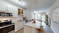 Located at 180 Woodruff Rd in Greenville, SC, this well-appointed 2-bedroom, 2-bathroom residence offers a thoughtfully designed single-level floor plan. The open-concept kitchen and living area serves as the heart of the home, featuring granite countertop islands with pendant lighting, crisp white cabinetry, subway tile backsplash, and a full suite of stainless steel appliances. Wood-style flooring flows throughout the main living areas, adding warmth and continuity. The bright living room benefits from natural light through large windows and is accented by a ceiling fan overhead. The generously sized primary bedroom features plush carpeting, a ceiling fan, and direct access to its en-suite bathroom, which boasts a dual-sink granite vanity and a marble-tiled soaking tub and shower combination. The second bathroom mirrors the same refined finishes, including wood-style flooring and a granite vanity. Both bedrooms are complemented by spacious closets equipped with wire shelving systems for organized storage. Neutral tones and clean architectural lines throughout create a cohesive, modern aesthetic that is both functional and inviting.