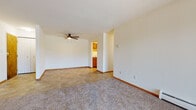 Located on High Ridge Trail in Fitchburg, Wisconsin, this single-floor residence offers a practical and comfortable layout throughout. The generous living area features a combination of plush carpeting and tile flooring, a ceiling fan, and baseboard heating, with a sliding glass door that invites natural light and provides outdoor access. A wall-mounted air conditioning unit ensures year-round comfort. The kitchen is efficiently designed with warm oak cabinetry, white appliances including a range, microwave, and refrigerator, and easy-to-maintain tile flooring. A hallway connects the living spaces to the private areas of the home. The bedrooms are well-proportioned, carpeted, and equipped with individual air conditioning units and windows fitted with blinds that allow for natural light. A standout feature is the spacious walk-in closet, outfitted with floor-to-ceiling wire shelving on both sides, providing exceptional storage capacity. The full bathroom includes a wood-toned vanity with a sink and mirror, a shower with a curtain, and hardwood-style flooring. Clean white walls and warm wood trim carry throughout, lending a consistent and neutral aesthetic across the entire space.