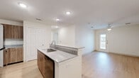 This single-floor, 4-bedroom, 2-bathroom residence offers a thoughtfully designed layout that maximizes functionality and comfort. Light hardwood flooring flows consistently throughout the entire space, creating a cohesive and modern aesthetic.

The open-concept kitchen serves as the heart of the home, featuring a granite-topped island with an integrated sink and built-in dishwasher, warm wood-tone cabinetry, and a full suite of black appliances including a range, microwave, and refrigerator. The kitchen opens directly into the living area, which is bathed in natural light from a glass exterior door that provides outdoor views and access.

Each of the four bedrooms is finished with the same light hardwood flooring and is equipped with a ceiling fan and light fixture. The bedrooms receive ample natural light through slatted-blind windows that frame views of the surrounding neighborhood. The primary bedroom offers a generous footprint suitable for a full furniture arrangement.

Both bathrooms are appointed with striking marble-style tile surrounds in the tub-shower combinations, complemented by chrome fixtures and hardwood-style flooring. Two dedicated closets and two hallways contribute to the practical storage and circulation of the home. The overall ambiance is clean, bright, and move-in ready, reflecting a contemporary residential design.