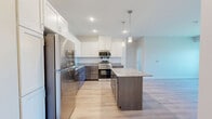 This well-appointed 2-bedroom, 3-bathroom residence in Rosemount, Minnesota offers a thoughtfully designed single-floor layout with contemporary finishes throughout. The kitchen serves as a standout centerpiece, featuring striking two-tone cabinetry with crisp white upper cabinets and rich dark lower cabinets, granite countertops, a central island, stainless steel appliances, and stylish pendant lighting — all set over light-toned hardwood-style flooring. The open layout flows seamlessly into the living room, which benefits from large windows with vertical blinds that invite natural light and provide outdoor views of the surrounding neighborhood. Both bedrooms are generously sized, finished with plush carpeting, and include windows that continue the theme of natural light throughout. The three bathrooms are finished with neutral tile flooring, white cabinetry, granite vanity tops, and tub-shower combinations, offering a clean and modern aesthetic. A dedicated laundry area houses a stacked washer and dryer alongside additional shelving for storage convenience. A separate closet provides further organizational space. The overall ambiance is bright, clean, and move-in ready, with consistent modern finishes tying each room together cohesively.