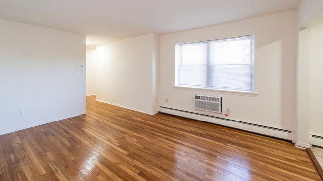 Adéntrate en el acogedor ambiente de los apartamentos Dorchester House. Esta espaciosa sala de estar cuenta con hermosos pisos de madera y abundante luz natural, ideal para crear recuerdos inolvidables. ¡Agenda tu visita hoy mismo para descubrir tu futuro hogar! - Dorchester House