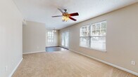 This single-floor residence offers a comfortable and functional layout designed to maximize livability. The expansive living area is finished with plush wall-to-wall carpeting and features a ceiling fan with light kit, large windows fitted with blinds that invite abundant natural light, and French doors that open to the exterior, creating a bright and airy atmosphere. An adjacent dining area is illuminated by an elegant chandelier and shares the same wood-look flooring that continues into the kitchen.

The galley-style kitchen is efficiently designed with warm honey-toned wood cabinetry, dark countertops, and a full suite of black appliances including a refrigerator, electric range, built-in microwave, and dishwasher. Wood-look flooring and a window overlooking the outdoors complete the kitchen's practical yet inviting character.

The bedrooms are generously proportioned, each featuring soft carpeting, ceiling fans, and windows that bring in natural light. The neutral beige tones throughout the bedrooms contribute to a calm, restful ambiance.

Two full bathrooms serve the residence. One features a single-sink vanity with warm wood cabinetry and a shower-tub combo, while the second bathroom offers a similarly styled vanity alongside a tub-shower unit, both finished with clean white fixtures and wood-look flooring.