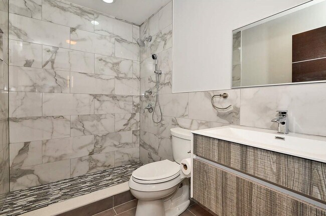 Designer bathroom with floor to ceiling porcelain tile, standup shower, Porcelanosa wall hung vanity and high end fixtures - 621 14th St