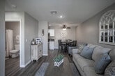Located at 10381 S Lynn Cir in Jurupa Valley, California, this single-story home presents a cohesive farmhouse-inspired aesthetic throughout its interior. The living room serves as the welcoming centerpiece of the home, featuring warm wood-look flooring, recessed lighting, and a front-facing window that draws in natural light. Paired arch-style decorative mirrors accent the neutral walls, adding architectural character to the space.

The living area flows seamlessly into the dining space, which is outfitted with a ceiling fan and a round dining table set beneath a large shiplap-style wall clock, reinforcing the home's casual, inviting style. Directly adjacent is the galley-style kitchen, efficiently designed with white cabinetry, granite-look countertops, a stainless steel sink, and black appliances including a gas range and refrigerator. A louvered interior door provides access to additional storage or utility space.

The bedroom is a comfortable, well-proportioned room with a ceiling fan, a window fitted with blinds, and wood-look flooring. The bathroom is clean and functional, featuring a full tub-shower combination with a curtain, white vanity cabinetry, and coordinating flooring throughout.