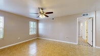 This single-floor space offers a clean, functional layout with tile flooring carried consistently throughout every room, creating a cohesive and easy-to-maintain interior. The main living area is generously sized, bathed in natural light through blinded windows, and equipped with a ceiling fan with integrated lighting. A second room of comparable size also features a ceiling fan and dual windows, providing excellent ventilation and brightness. The galley-style kitchen is efficiently designed with ample cabinetry on both sides, gray laminate countertops, a double sink, and white appliances including a range and refrigerator, making the most of the available space. An additional room offers versatile use and connects directly to a dedicated walk-in closet, providing substantial storage with a built-in hanging rod. The bathroom is straightforward and well-appointed, featuring a white vanity with storage cabinetry, a toilet, chrome towel bars, and tile flooring that complements the rest of the home. Neutral warm-toned walls throughout lend a calm, welcoming ambiance, while the consistent use of white trim and baseboards adds a clean, polished finish to every space. The overall layout is practical, efficient, and well-suited for comfortable everyday living.