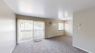 Located at 2890 S Ninth St in Kalamazoo, Michigan, this two-bedroom, one-bathroom unit offers a practical and comfortable single-floor layout. The living room is a welcoming space featuring soft carpet flooring, a large sliding glass door with vertical blinds that invites natural light and provides outdoor access, a wall-mounted air conditioning unit, and a baseboard heating system. A pendant light fixture adds a subtle decorative touch near the dining area, which transitions seamlessly from the living space into the kitchen. The galley-style kitchen is efficiently designed with white cabinetry, laminate countertops, and a full suite of white appliances including a refrigerator, electric range, microwave, and dishwasher. Light wood-look flooring runs throughout the kitchen, continuing into the bathroom. The two bedrooms are carpeted and finished in neutral tones, each offering natural light through windows and closet storage with bi-fold doors. The primary bedroom is generously sized and includes a built-in closet with shelving. The bathroom features a clean, white tub/shower combo, a vanity with mirror, and wood-look flooring. Neutral wall tones and clean finishes throughout give the space a bright and move-in-ready feel.