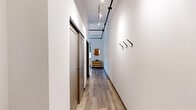 Located on the 6th floor of 305 Michigan Ave in the heart of downtown Detroit, this efficiently designed unit offers a well-organized layout across a single floor. The entry hallway sets a modern tone with wood-look flooring, exposed black metal track lighting overhead, and built-in wall hooks for coats and accessories — a practical yet stylish introduction to the space.

The open living and dining area doubles as a bedroom, maximizing every square foot. A bold, textured feature wall provides a striking focal point, while large windows fitted with roller shades frame panoramic views of the Detroit skyline, allowing natural light to fill the room. Exposed industrial-style ceiling rails add an urban loft character throughout.

The kitchen is fully equipped with stainless steel appliances — including a refrigerator, range, microwave, and dishwasher — set against crisp white cabinetry and light countertops. The tall ceilings in this area enhance the sense of openness.

The bathroom is clean and functional, featuring a single-sink vanity with a large mirror, wood-look tile flooring, and white fixtures. Two closets provide ample storage for a space of this scale.

This unit delivers a modern urban living experience in a prime downtown Detroit location.