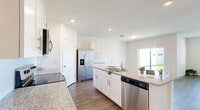 Located on Peaceful Brook Loop in Punta Gorda, Florida, this single-story home offers a thoughtfully designed layout across a generously sized floor plan. The interior is finished with light wood-look flooring throughout, recessed lighting, and a neutral color palette that enhances the bright, airy atmosphere in every room.

The kitchen serves as the heart of the home, featuring white shaker cabinetry, granite countertops, subway tile backsplash, a central island with a sink, and a full suite of stainless steel appliances. It flows seamlessly into the combined dining and living area, creating an open, functional space well-suited for everyday living. A sliding glass door provides direct access to a paved outdoor patio with a fenced backyard.

The four bedrooms are comfortably sized, each with wood-look flooring, windows for natural light, and ceiling fans. The generously proportioned primary bedroom connects to a private en-suite bathroom with a granite-topped vanity, walk-in shower, and access to a walk-in closet with built-in shelving. The second bathroom serves the remaining bedrooms. A dedicated laundry room with full-size washer and dryer completes this well-appointed home.