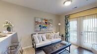 Located at 40 Hutchinson Ave in Columbus, Ohio, this well-appointed single-floor residence offers a thoughtfully designed layout with comfortable living spaces throughout. The living room serves as a welcoming centerpiece, featuring plush carpeting, neutral warm-toned walls, and a sliding glass door framed by decorative curtains that allows natural light to fill the space. The kitchen is outfitted with dark espresso cabinetry, granite-style countertops, a classic white subway tile backsplash, and stainless steel appliances, including a range, microwave, and refrigerator, all set atop rich hardwood-style flooring. Two well-sized bedrooms offer carpeted floors, large windows with outdoor views, and ample space for both rest and work. Each bedroom is served by its own bathroom: one features a spacious walk-in shower with sliding glass doors and a dark-cabinetry vanity with stone-look countertops, while the second offers a matching vanity with a generous mirror. A dedicated in-unit laundry room provides added convenience, complete with a full-size washer and dryer and additional storage. Throughout the residence, consistent warm neutral tones, wood-look flooring in wet areas, and an understated modern aesthetic create a cohesive and inviting atmosphere.