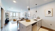 Located at 2 Chestnut St in Norwalk, CT, this well-appointed one-bedroom, one-bathroom residence offers a thoughtfully designed layout with modern finishes throughout. Hardwood-style flooring flows consistently across the entire space, lending a cohesive and polished look.

The open-concept kitchen and living area serves as the heart of the home. The kitchen is equipped with stainless steel appliances, sleek white cabinetry, a subway tile backsplash, and a generous peninsula with a quartz countertop and breakfast bar seating, illuminated by stylish pendant lighting. The adjoining living room benefits from expansive floor-to-ceiling windows that flood the space with natural light and offer open views of the surrounding neighborhood.

The bedroom is a comfortable retreat, featuring large windows that invite additional natural light and views of the exterior. A wall-mounted mini-split unit provides individual climate control. The room also benefits from convenient closet storage.

The bathroom is clean and contemporary, showcasing a glass-enclosed walk-in shower with white tile surround and hardwood-style flooring that carries throughout. A dedicated closet provides additional organization.

The overall ambiance is bright, airy, and modern — a well-balanced residence ideal for those seeking a stylish and functional living space in Norwalk, CT.