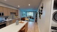 Located at 430 Jackson St in Oakland, CA, this single-floor residence offers a thoughtfully designed open-concept layout that seamlessly connects the kitchen, dining, and living areas. The kitchen is a standout feature, outfitted with warm wood flat-front cabinetry, a full suite of stainless steel appliances including a refrigerator, range, microwave, and dishwasher, a tile backsplash, and a generous marble-topped island with bar seating — ideal for both meal preparation and casual dining. Light hardwood flooring runs throughout, complementing the soft, neutral wall tones that lend the space a calm, contemporary ambiance. The open living area is generously proportioned, bathed in natural light from a large window that overlooks the surrounding neighborhood. A vertical wall planter adds a touch of greenery and personality to the main living corridor. The bedroom is a serene retreat, featuring large windows that frame views of an adjacent outdoor terrace, allowing abundant natural light to fill the room. The bathroom is finished in a clean, minimalist style with light hardwood flooring, a wall-mounted toilet, and a shower-tub combination. Recessed lighting throughout the home provides consistent, well-distributed illumination, enhancing the modern aesthetic of this well-appointed Oakland residence.