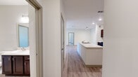 This thoughtfully designed 2-bedroom, 2-bathroom residence is laid out on a single floor, offering a comfortable and functional living environment. The open-concept kitchen and living area serves as the heart of the home, featuring light-toned hardwood-style flooring that flows seamlessly throughout the common spaces. The kitchen is equipped with dark espresso cabinetry, black appliances including a refrigerator, stove, and microwave, and a generous center island with an integrated sink and clean white countertops — ideal for both cooking and casual dining.

The primary bedroom is a spacious retreat with plush carpeting, a ceiling fan, and a large window that invites natural light and outdoor views. The second bedroom also features light hardwood-style flooring and direct access to adjoining spaces. Both bathrooms are finished with dark vanity cabinetry, white countertops, large mirrors, and tile flooring; one bathroom includes a walk-in shower stall.

A dedicated closet provides additional storage, while the private balcony — accessible from the living area — offers open views of the surrounding landscape and neighboring buildings under an open sky. Recessed lighting throughout the home ensures a bright and inviting ambiance across all rooms.