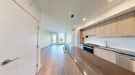 This well-appointed 4-bedroom, 2-bathroom unit in Calgary, AB offers a modern, contemporary design with clean lines and a bright, neutral palette throughout. The open-concept kitchen and living area serves as the heart of the home, featuring light wood cabinetry extending to the ceiling, stainless steel appliances, a striking stone-topped island with pendant lighting, and light hardwood flooring that flows seamlessly into the living space. Large windows in the living area frame views of surrounding greenery, filling the space with natural light.

The four bedrooms maintain the same clean aesthetic, with light hardwood floors, crisp white walls, and windows overlooking outdoor green spaces including views of a sports field, providing a refreshing connection to the outdoors. The primary bedroom, while compact, is efficiently designed to maximize functionality.

The two bathrooms are finished with large-format dark tile flooring and light wood vanities topped with dark stone counters. One bathroom features a soaker tub with a tiled surround, while the second offers a frameless glass walk-in shower. Recessed lighting and large mirrors enhance the sense of space in both. A connecting hallway ties all rooms together, completing this efficiently laid-out, modern home.