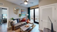 Located at 405 S Main St in the heart of Ann Arbor, Michigan, this well-appointed 2-bedroom, 2-bathroom unit is thoughtfully designed to maximize every square foot of its single-floor layout. A welcoming entrance hallway leads into the open-concept living and dining area, where light wood-tone flooring, a ceiling fan, and sliding glass doors to a private balcony create a bright, airy atmosphere with city views. The modern kitchen is a standout feature, showcasing sleek white upper cabinetry, dark lower cabinets, stainless steel appliances including a refrigerator, microwave, and range, and a peninsula with quartz countertops that seats multiple guests — ideal for both everyday meals and entertaining. The primary bedroom offers corner windows that invite natural light and urban views, complemented by a ceiling fan for added comfort. The second bedroom is a cozy, well-proportioned space. Both bathrooms are finished with floating dark-wood vanities, quartz countertops, and contemporary vanity lighting. Additional practical features include three closets, a dedicated laundry area, and a utility room, ensuring ample storage throughout. The unit's neutral warm-gray palette and wood-look flooring provide a cohesive, modern aesthetic throughout.