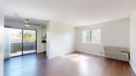 Located at 12046 Emelita St, Unit 202 in Los Angeles, this one-bedroom, one-bathroom residence offers a thoughtfully organized single-floor layout. The kitchen is a functional highlight, featuring stainless steel appliances including a gas range, over-the-range microwave, and dishwasher, complemented by white shaker-style cabinetry, grey countertops, and a corner sink beneath a multi-pane window that brings in natural light. Hardwood-style flooring runs throughout the kitchen and living areas, adding warmth and continuity to the space. The bedroom is a comfortable, carpeted retreat with a wide window framing leafy outdoor views, filling the room with natural light. It connects directly to a dedicated walk-in closet equipped with built-in shelving rods, offering practical storage solutions. The bathroom is clean and straightforward, featuring a full tub-shower combination with chrome fixtures, a white vanity with grey countertop, and wood-style flooring. A hallway connects the main areas of the unit, contributing to a logical and efficient flow throughout. The overall ambiance is bright, neutral, and move-in ready, making it a practical and comfortable urban residence in the heart of Los Angeles.