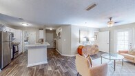 Located at 1400 Boxwood Blvd in Columbus, Georgia, this single-floor residence offers a thoughtfully designed open-concept layout that seamlessly connects the main living areas. The kitchen is a functional centerpiece, featuring white cabinetry, granite-style countertops, stainless steel appliances including a refrigerator, microwave, and range, and a peninsula with a built-in sink that doubles as a breakfast bar. Dark hardwood-style flooring extends throughout the main living and kitchen areas, adding warmth and visual continuity.

The living room is generously proportioned, offering ample space for multiple seating arrangements and benefiting from natural light through the windows. A hallway leads to the private quarters, where the bedrooms are carpeted for comfort. Each bedroom includes a closet with double doors, and the rooms provide a calm, restful atmosphere. One bedroom features a window overlooking the outdoors.

The bathroom is well-equipped with a granite-topped vanity with white cabinetry, dark tile flooring that complements the rest of the home, and a shower-tub combination. Textured ceilings are consistent throughout the residence. The overall design palette — neutral tones, clean lines, and contemporary fixtures — creates a cohesive and inviting living environment suited for everyday comfort.