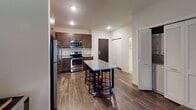 Located at 735 Raymond Ave in Saint Paul, Minnesota, this contemporary single-floor residence offers a well-designed open-concept layout that seamlessly connects the kitchen, dining, and living areas. The kitchen is a standout feature, showcasing rich dark-stained cabinetry, granite countertops, a full suite of stainless steel appliances including a refrigerator, dishwasher, microwave, and range, as well as a movable granite-topped island with bar seating—ideal for both cooking and casual dining. Durable wood-style flooring runs throughout the main living areas, adding warmth and continuity to the space. The living room is bright and inviting, anchored by large sliding glass doors that open to a private balcony, filling the room with natural light and offering outdoor views. The space includes two bedrooms, each featuring plush carpeting, generous windows with blinds, and ample closet storage. The neutral tones and clean lines throughout create a calm, modern ambiance. The bathroom is finished with a white vanity, a large mirror, and clean, minimal fixtures. Recessed lighting throughout the unit provides consistent, well-distributed illumination. This thoughtfully designed residence combines functional layout with modern finishes in a prime Saint Paul location.