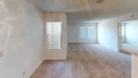 This single-floor residence is designed with a practical, open-concept layout that connects the living area and kitchen seamlessly. The living room is generously sized, finished with neutral carpet, a ceiling fan, and a sliding glass door fitted with vertical blinds that fills the space with natural light and provides access to an outdoor area. The textured ceilings are consistent throughout the unit, contributing to its classic character.

The kitchen is arranged in a galley style and opens to the living area via a peninsula counter. It features light wood cabinetry offering ample storage, white appliances including a gas range and refrigerator, a stainless steel sink, and tile flooring beneath a recessed overhead light panel.

The unit includes multiple bedrooms, each carpeted and well-lit by windows with outdoor views. Bedrooms are equipped with sliding-door closets, some featuring built-in shelving for added organization. The neutral wall tones carry throughout, maintaining a cohesive, bright atmosphere.

Two full bathrooms are present, each featuring a tub-and-shower combination with white tile surrounds, chrome fixtures, and built-in shelf niches. The overall layout is functional and well-organized, offering comfortable, move-in-ready living.
