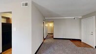 Located at 1803 Village Green Blvd in Jeffersonville, Indiana, this apartment offers a practical and well-organized single-floor layout with two bedrooms, three bathrooms, and four closets. The living room is a generously sized, carpeted space filled with natural light from a large window, providing a comfortable and open feel. Adjacent to the living area is a dedicated dining room, creating a natural flow for everyday living and entertaining. The kitchen features warm wood-tone cabinetry, granite-style laminate countertops, hardwood-style flooring, and black appliances including a refrigerator, dishwasher, and range. A utility closet within the kitchen houses the water heater. Both bedrooms are carpeted and receive natural light through windows with outdoor views of surrounding greenery. The spacious primary bedroom includes dedicated closet space with built-in shelving. The bathrooms are appointed with wood-toned vanities and white fixtures; at least one includes a full bathtub and shower combination with hardwood-style flooring. A central hallway connects the rooms efficiently, and textured ceilings are consistent throughout. The unit's neutral color palette and functional layout make it a versatile and move-in-ready residence.