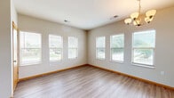 Located at 301 E Main St in Waunakee, WI, this well-appointed 2-bedroom, 3-bathroom unit offers a functional and comfortable single-floor layout. The open-concept dining and kitchen area is a standout feature, showcasing rich dark-wood cabinetry, stainless steel appliances including a range, microwave, and refrigerator, and a peninsula with a built-in sink and pendant lighting overhead. The kitchen flows seamlessly into the dining area, which is brightened by multiple windows dressed with blinds and accented by an elegant chandelier. Durable hardwood-style flooring runs throughout the main living and kitchen areas, complemented by warm wood baseboards that add a polished finish. Both bedrooms are generously sized and carpeted for comfort, with windows providing natural light and views of the surrounding area. The primary bedroom includes access to a dedicated closet. The three bathrooms are clean and functional, each featuring hardwood-style flooring, a vanity with dark cabinetry and light countertops, and at least one bath/shower combination with modern chrome fixtures. The overall ambiance is bright, neutral, and move-in ready, making this a practical and inviting space in the heart of Waunakee.