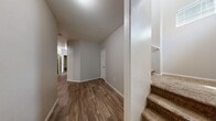 Located in North Las Vegas, NV, this two-story home offers three bedrooms, three bathrooms, and a well-organized layout across two floors. The main level features an open-concept kitchen and living area with warm-toned wood-look tile flooring, honey-oak cabinetry, a breakfast bar with decorative corbels, and recessed lighting. The living room is carpeted and spacious, illuminated by a pendant light. A hallway with durable wood-look flooring connects the main living spaces, with carpeted stairs leading to the upper level. The ground floor also includes an attached garage with a concrete floor and automatic opener, as well as a dedicated laundry room equipped with a full-size washer and dryer and built-in shelving. Upstairs, the three bedrooms feature plush carpeting and natural light from windows. The generously sized primary bedroom includes a walk-in closet with wrap-around wire shelving. The bathrooms are cleanly appointed with wood-look flooring, single-sink vanities with wood cabinetry, and tub-shower combinations. Two closets provide ample storage throughout. The home's neutral color palette and textured ceilings create a clean, move-in ready atmosphere throughout.